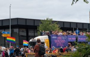 Demonstrierende des CSD Berlin, z.B. mit Regenbogenflagge, und ein Lkw, auf dem ebenfalls Demonstrierende stehen und an dem eine Plane mit dem CSD-Motto "Nie wieder still!" hängt.
